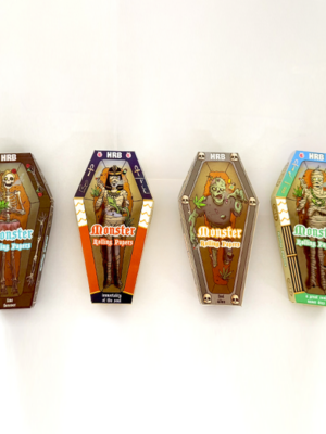 Four coffin-shaped Monster Rolling Papers boxes in brown, orange, gray, and teal, each with a cartoon monster on a white background in a row.